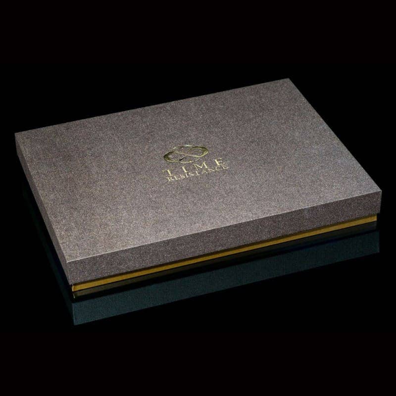 Gray textured box with gold accents and a logo on a black background