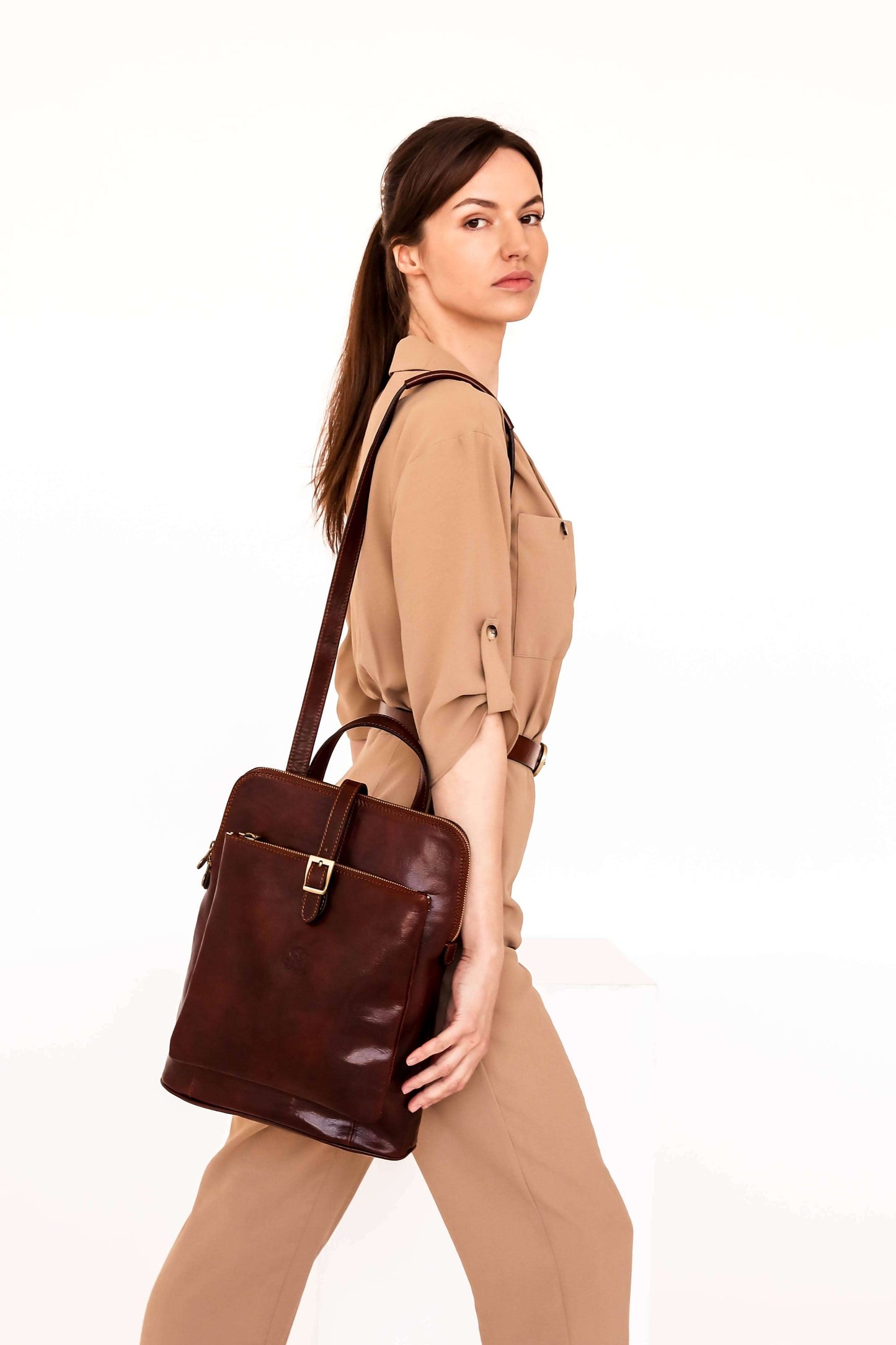 Woman holding a brown leather bag against a white background