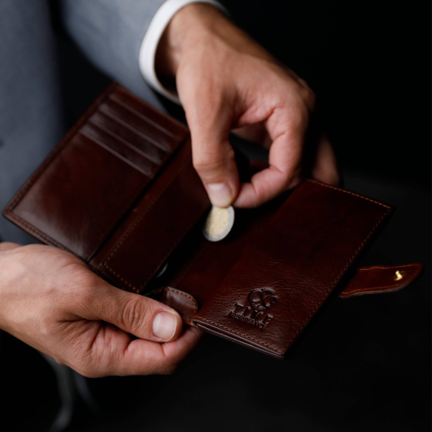 Person holding a brown leather wallet with a coin purse feature.