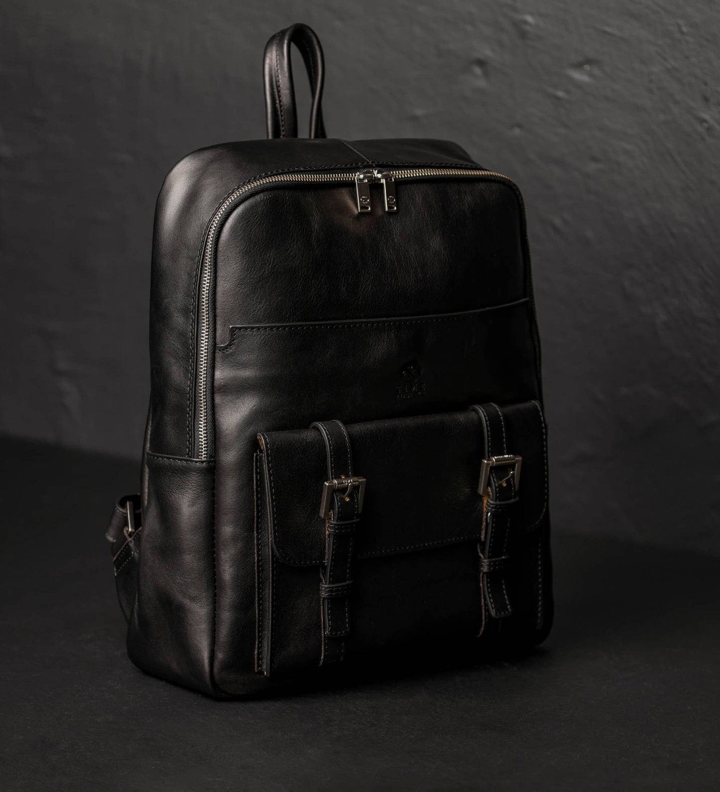 Black leather backpack on a dark background