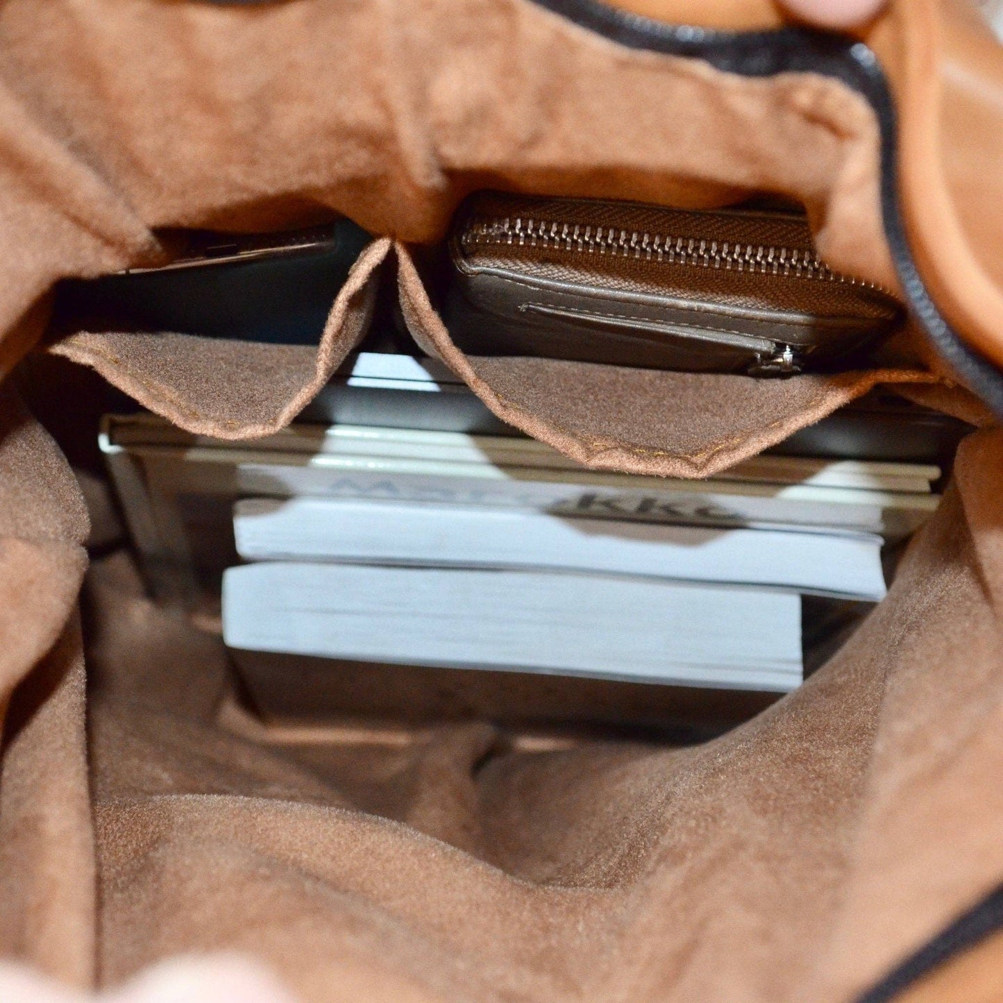 Close-up of a brown leather bag with a stack of white cards inside.