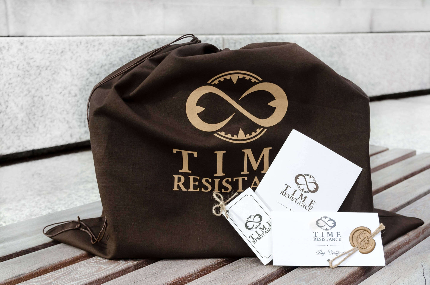 Brown drawstring bag with 'Time Resistance' logo on a wooden surface