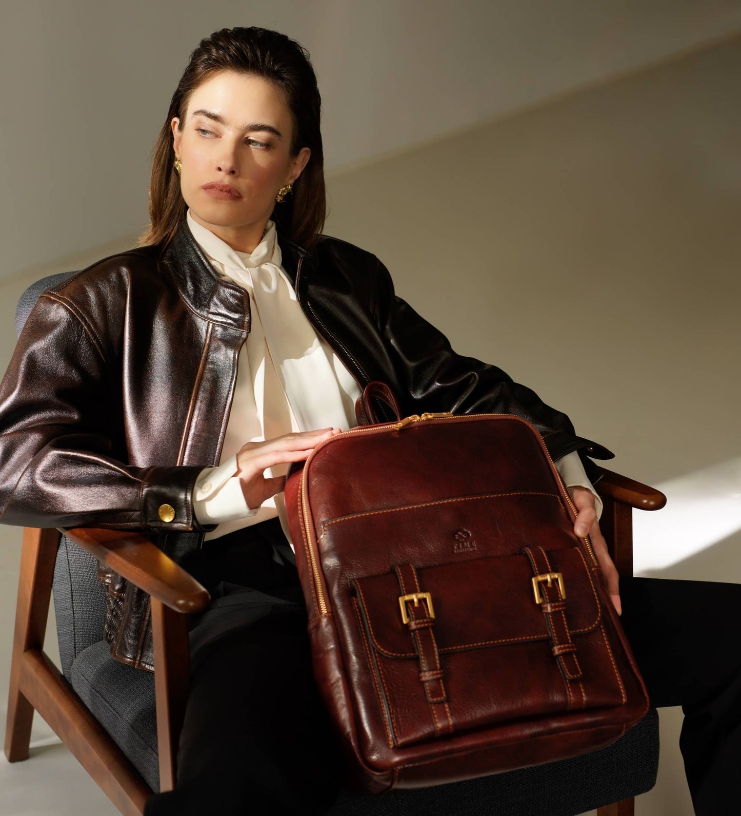 Woman holding a brown leather briefcase in an indoor setting