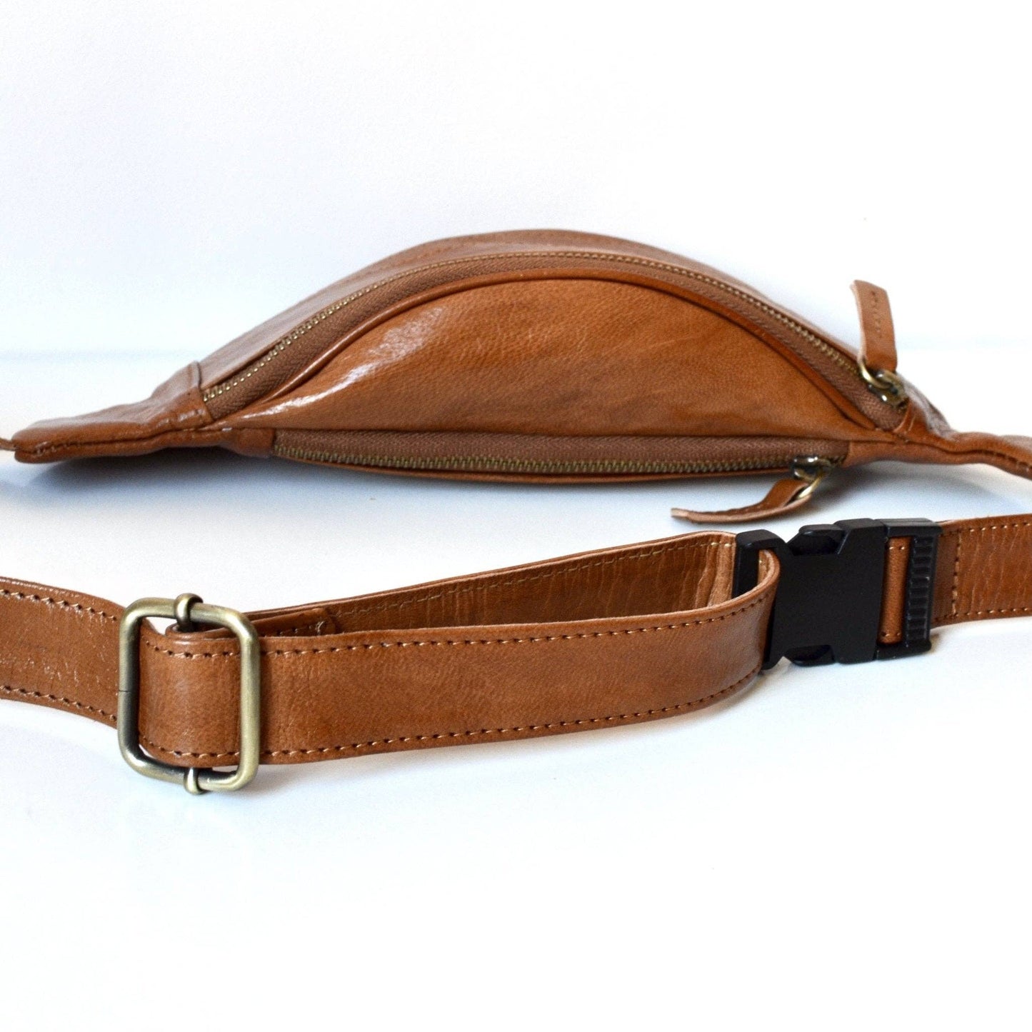 Brown leather waist bag with a strap on a white background