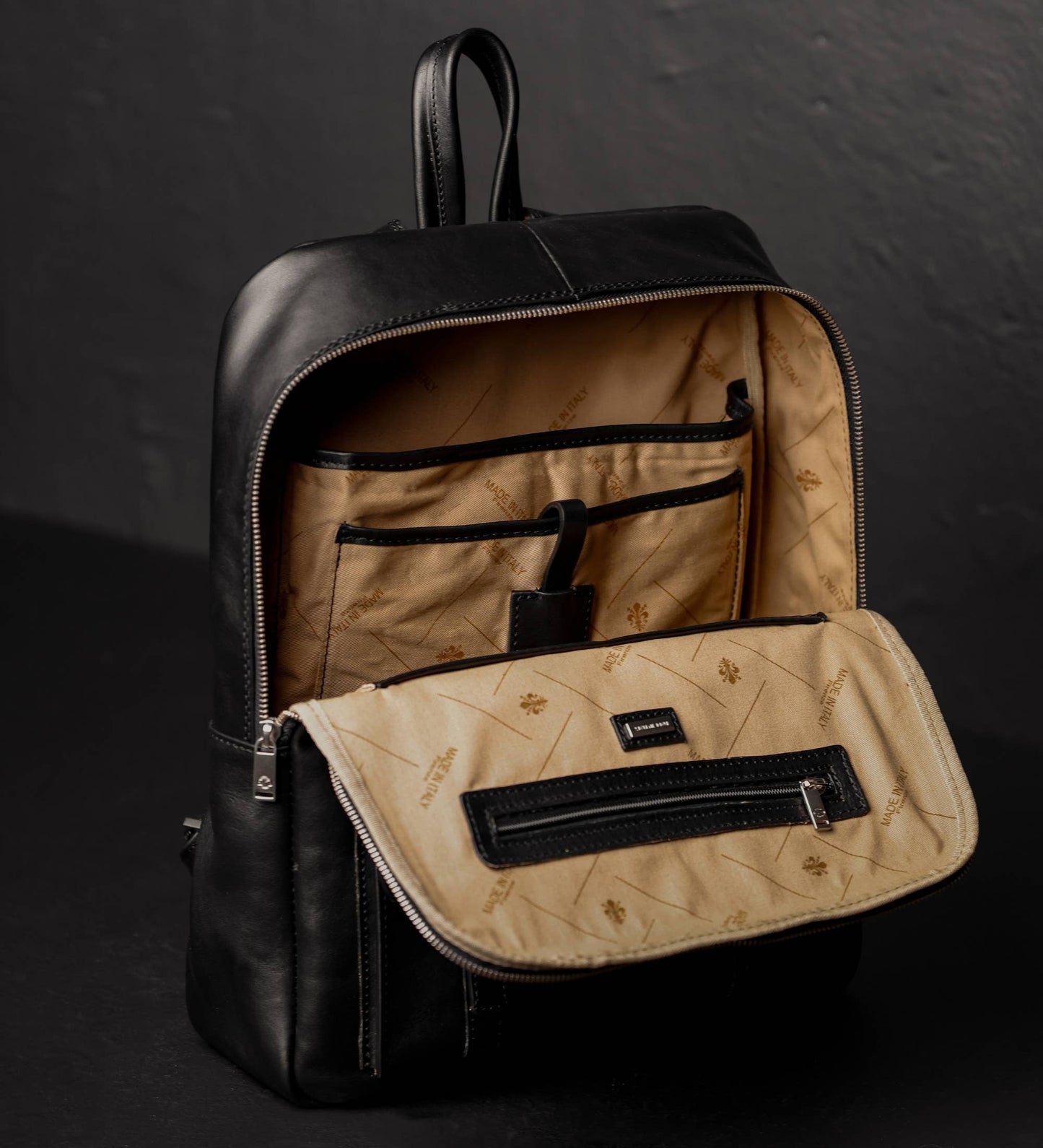 Black backpack with beige interior on a dark background