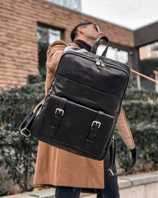 Homme portant un sac à dos en cuir noir, idéal pour un look élégant et fonctionnel.