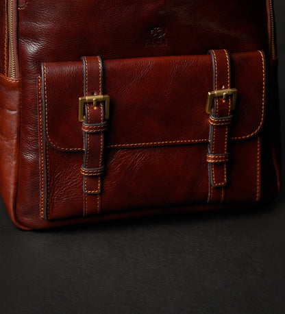 Close-up of a brown leather bag with gold buckles on a black background