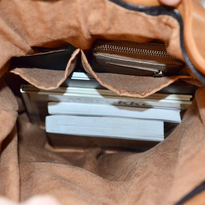 Close-up of a brown leather bag with a stack of white cards inside.
