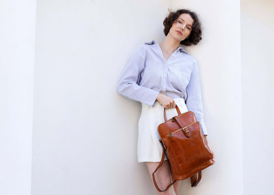 Woman holding a brown leather bag against a white background