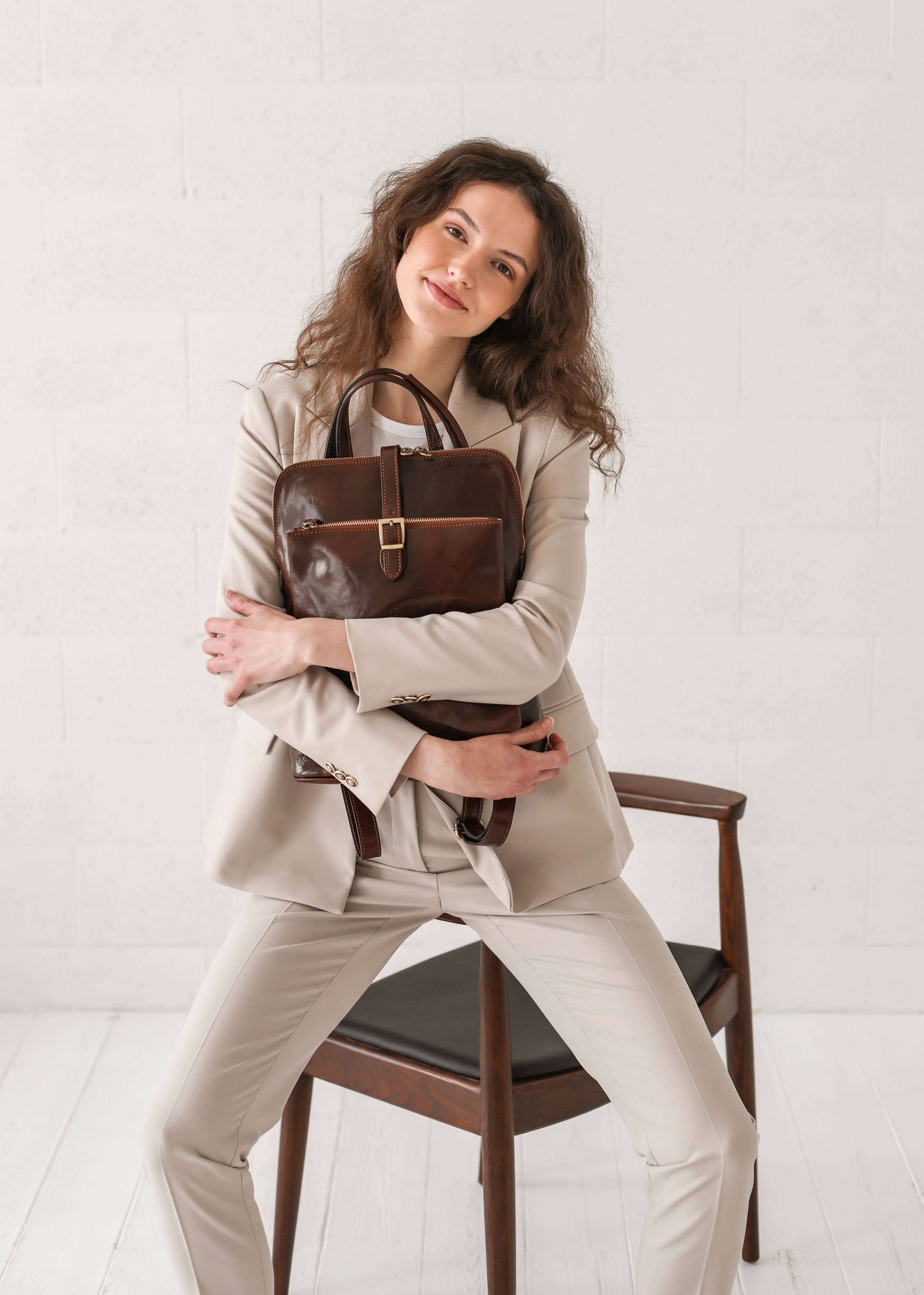 Woman holding a brown leather bag against a white background