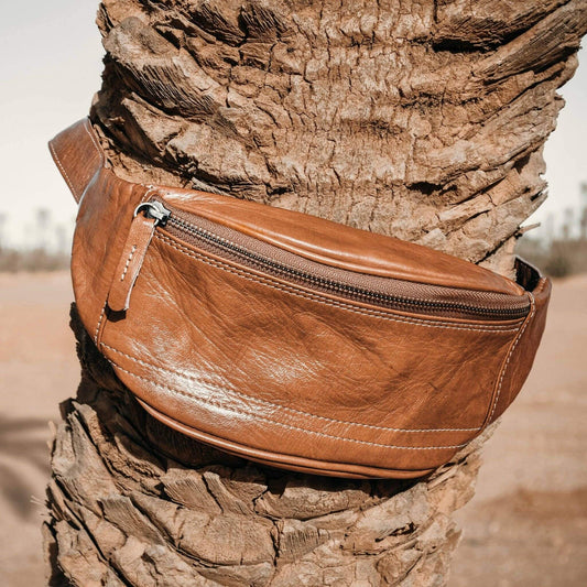 Brown leather waist bag on a tree stump with a natural background