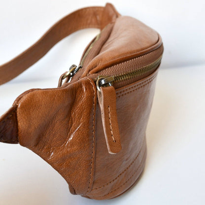 Brown leather waist bag with gold zipper on a white background
